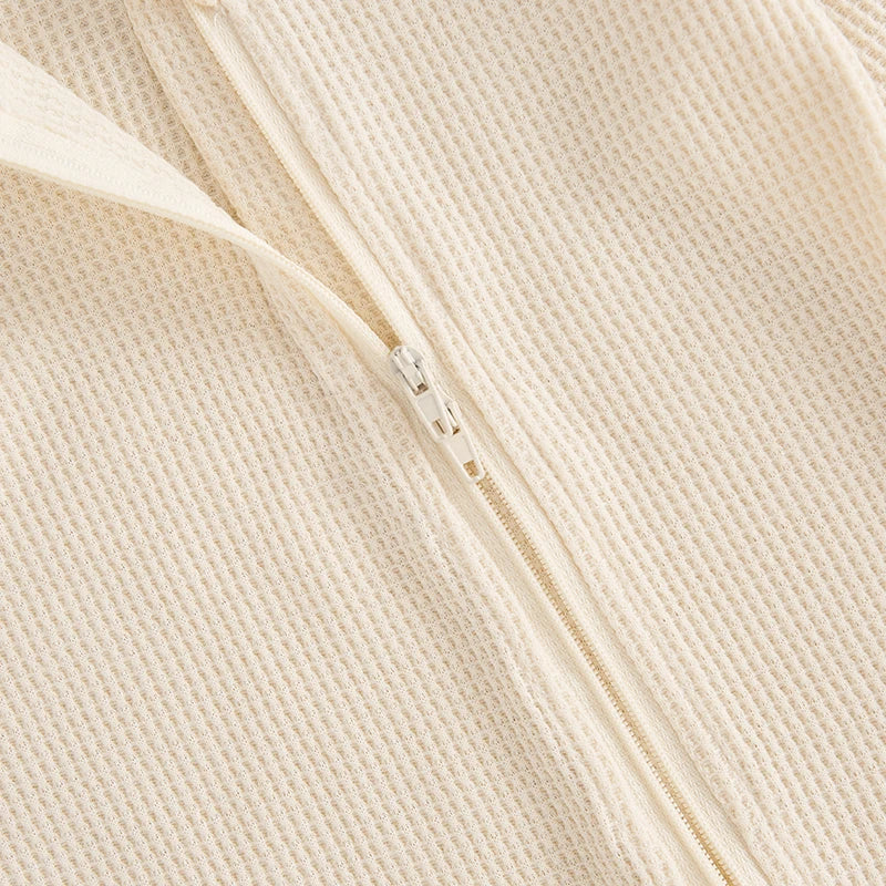 Newborn baby in waffle knit footed romper with hat